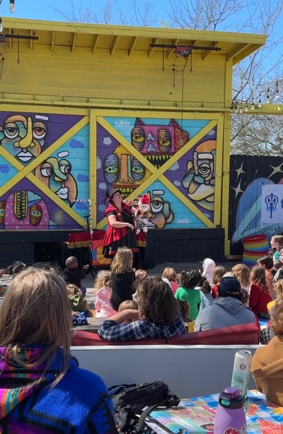 Funny Honey performing with a puppet while children watch